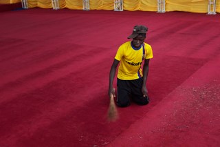 Um voluntário varre o tapete antes da chegada de Bento XVI