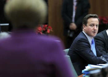 <p>David Cameron olha para Angela Merkel, na cimeira em Bruxelas</p>