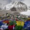 Bandeiras de oração budista flutuam ao vento com o acampamento de Evereste visto ao fundo