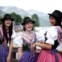 Algumas raparigas assistem ao desfile de barcos junto ao lago Grundlsee nos seus vestidos tradicionais Dirndl