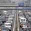 China, Pequim, 12.08.2011 | Peões atravessam uma ponte sobre o mar   de automóveis que crescentemente invade a capital chinesa. A venda   de carros continua em alta e as bicicletas vão sendo deixadas de lado. 