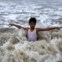 ÍNDIA, 06.06.2012. Um rapaz brinca nas águas do Mar Arábico durante uma chuva de pré-monção em Mumbai 