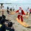 Indonésia, na ilha de Bali, praia de Kuta. Vestido de Pai Natal, o sufista dá aulas a crianças de um orfanato antes de os levar a surfar