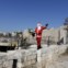 O israelo-árabe Issa Kassissieh, vestido de Pai Natal, segura uma pequena árvore de Natal no centro histórico de Jerusalém 