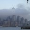 Nova Iorque, ao longo do rio Hudson enquanto as nuvens envolvem o One World Trade Center. 