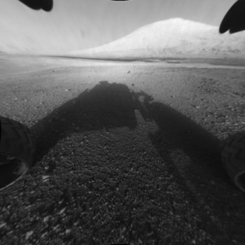 Ao longe, entre as poeiras que tapam a câmara do <i>Curiosity</i>, surge uma encosta da cratera Gale