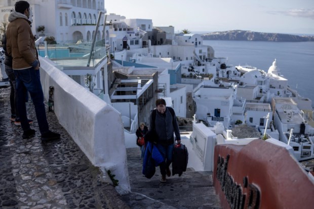 Turistas carregam as suas bagagens enquanto abandonam a aldeia de Fira, em Santorini