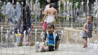 Menino brinca na fonte de um parque em Nakano num dia em que temperaturas dispararam 