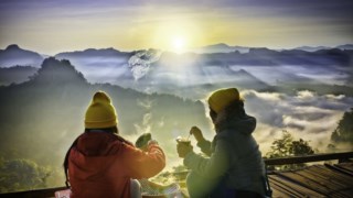 Group of normadic traveler in motion of enjoy takes food instant breakfast on the peak of mountain in the morning, enjoy having meal together in the mist foggy flowing in between the mountains hills