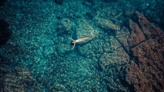 Aerial view of a woman floating in the Mediterranean coast