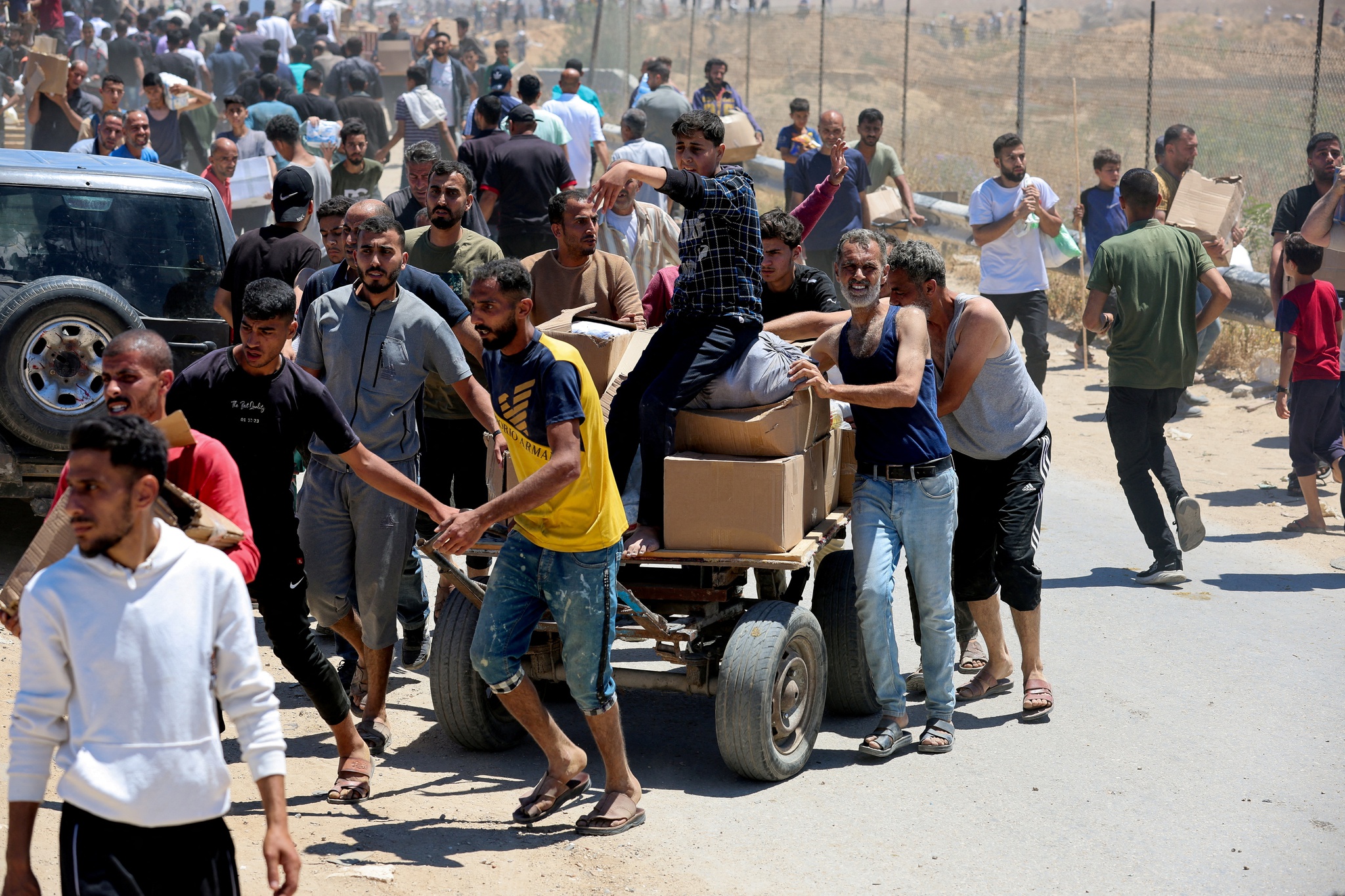 Palestinians walk with aid supplies which they received from the U.S.-backed Gaza Humanitarian Foundation, in the central Gaza Strip, May 29, 2025. REUTERS/Ramadan Abed REFILE - CORRECTING LOCATION FROM "NEAR AN AREA OF GAZA KNOWN AS THE NETZARIM CORRIDOR" TO "IN THE CENTRAL GAZA STRIP".