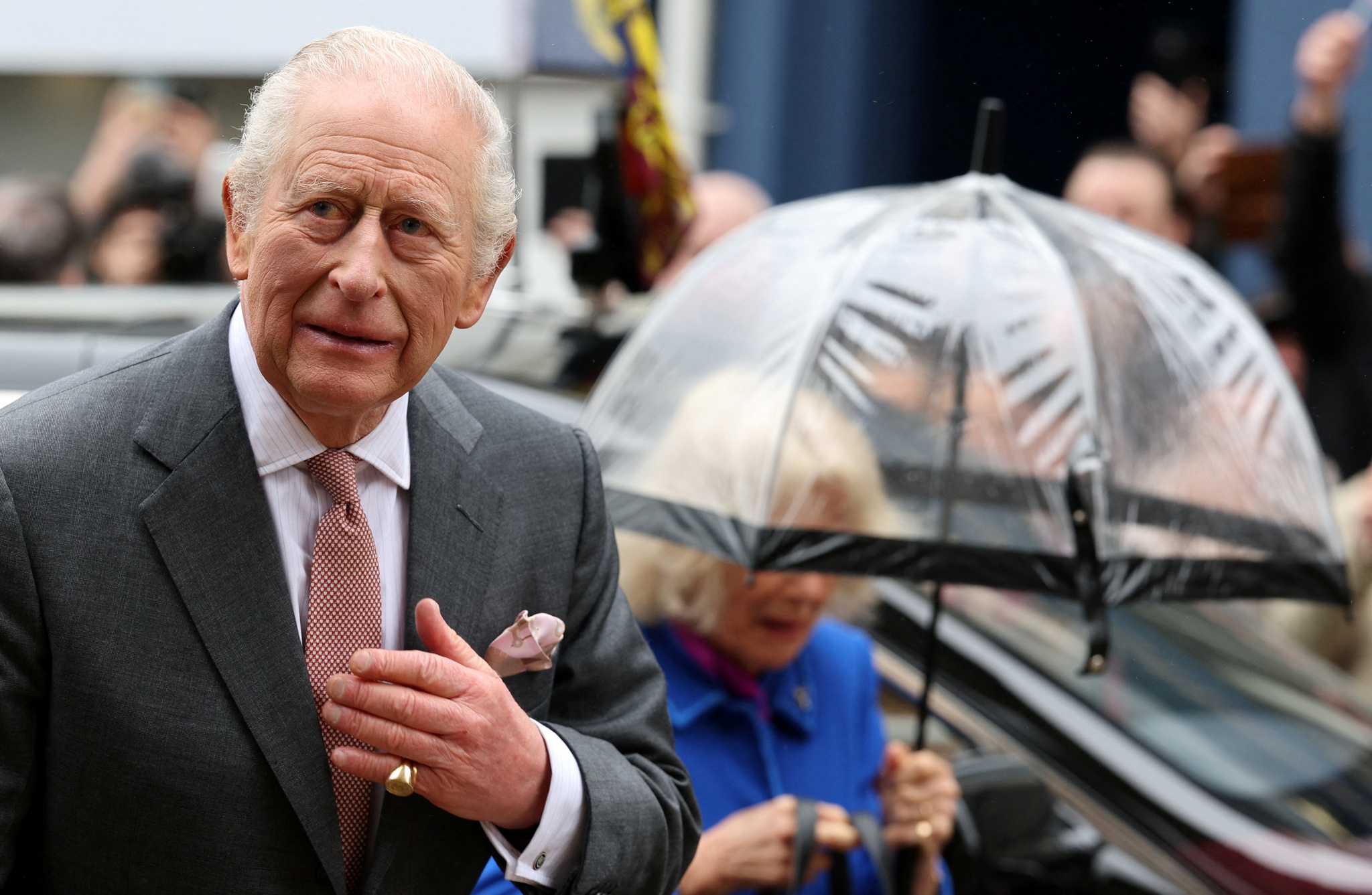 Britain's Queen Camilla shelters from the rain beneath an umbrella as she and King Charles arrive to visit Holy Trinity Church in St Austell, Britain, March 24, 2026. ADRIAN DENNIS/Pool via REUTERS