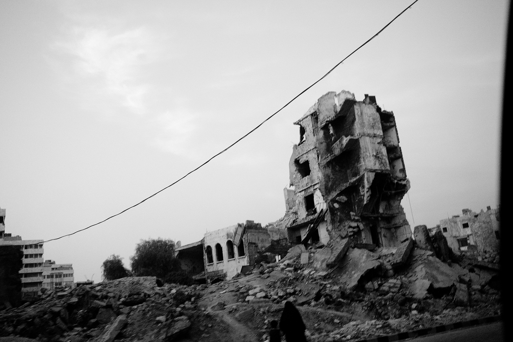 Aleppo, norte da Síria. Uma mulher e uma criança caminham numa área que foi bombardeada. Não muito longe deste lugar, mesmo depois da queda do regime, em 2024, ainda se mantém activa uma frente de guerra